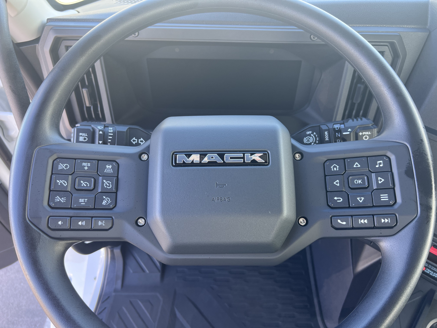 Mack AN64T steering wheel with control buttons on both sides and Mack logo center.