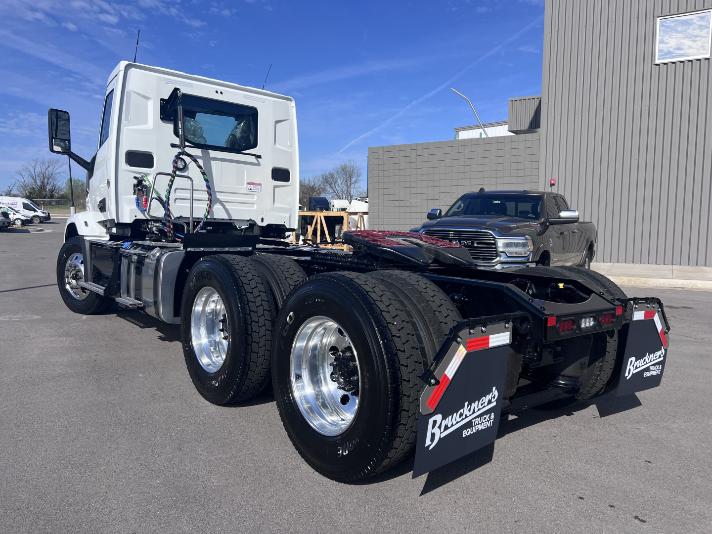 Truck chassis with dual rear axles and white daycab, Mack AN64T, visible fuel tanks, hydraulic lines, and trailer connection area.