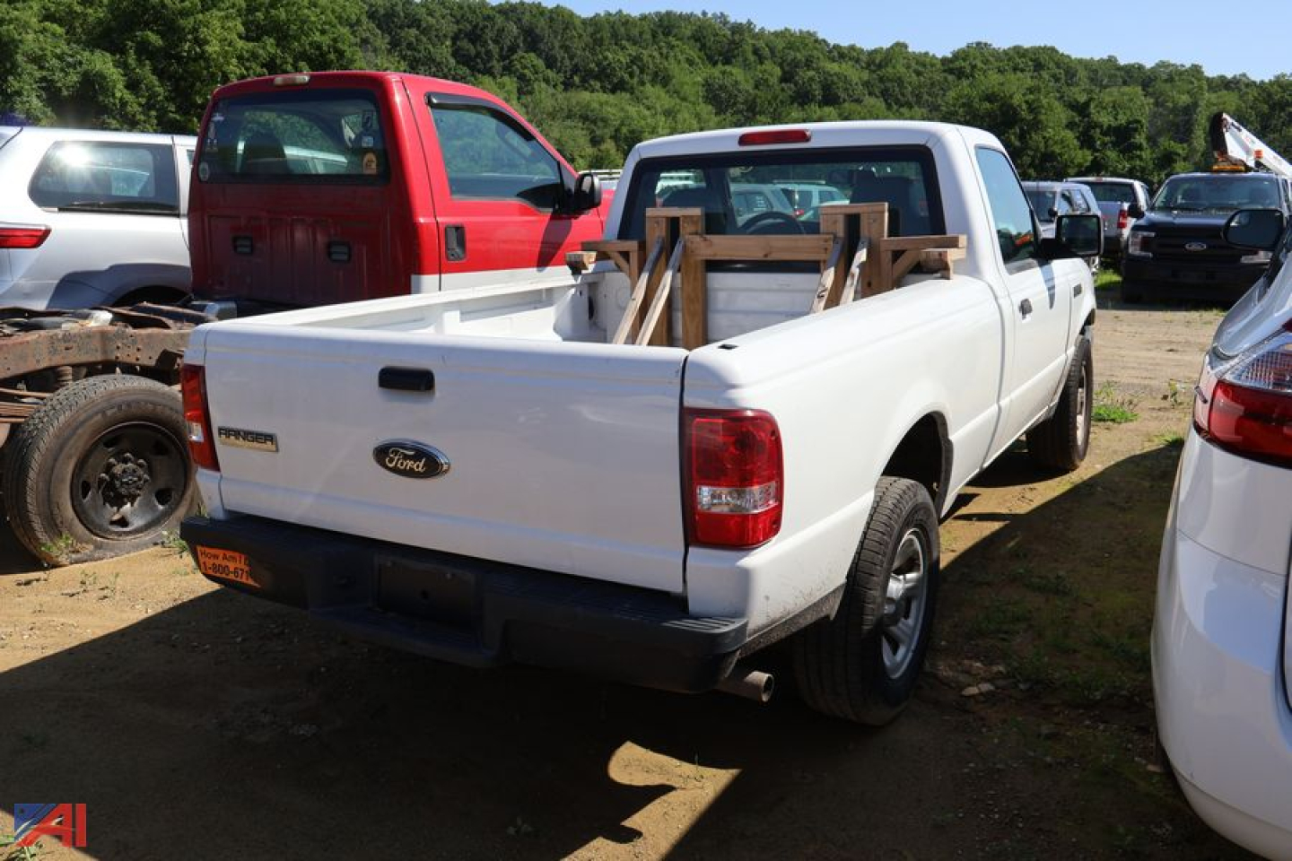 Ford Ranger pickup truck rear view showing white two-door, long bed, with wooden supports in bed and Ford emblem on tailgate.