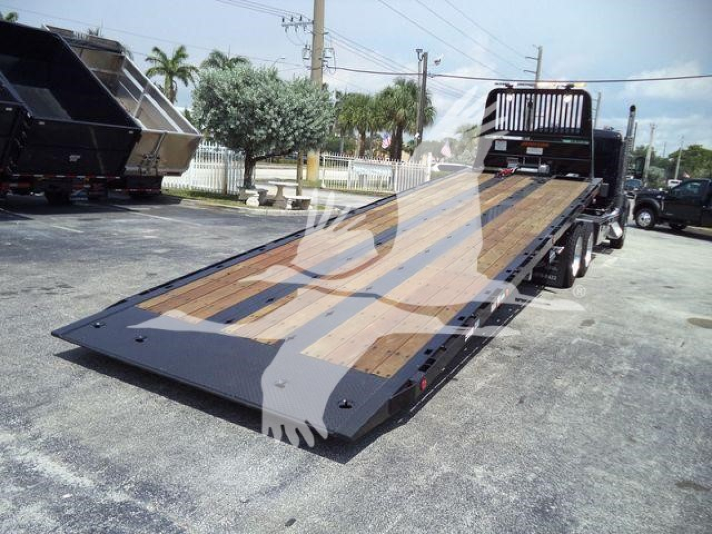 Truck rollback bed with wooden decking and ramps, Kenworth T880 setup on trailer.