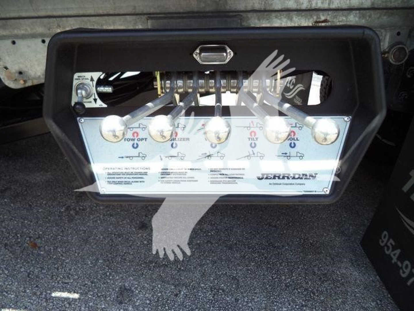 Control panel with multiple levers and labels mounted on a Kenworth T880 rollback truck setup showing four lever handles and instructional text.