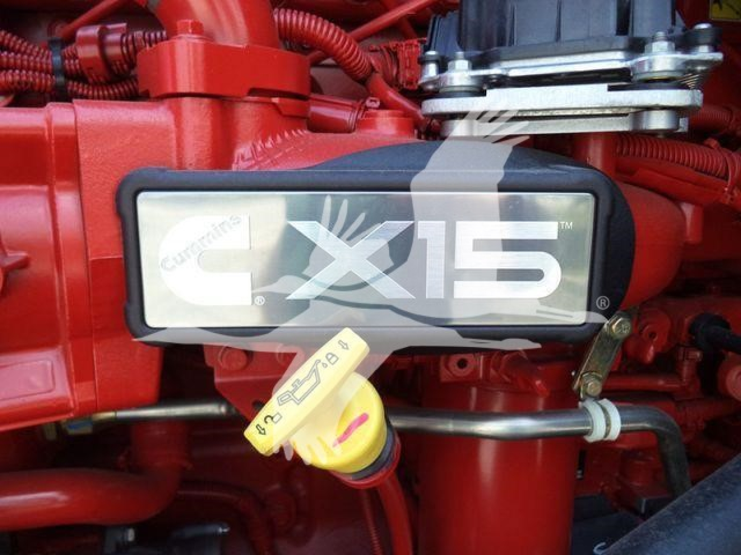 Kenworth T880 engine bay showing CX15 emblem and yellow protective tag on fluid line.