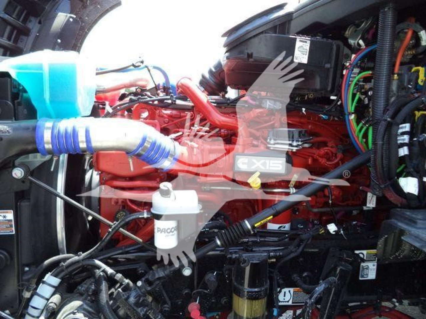Kenworth T880 engine bay with EXIS5 label on red engine, various hoses, wiring, coolant reservoir, and air intake components visible.