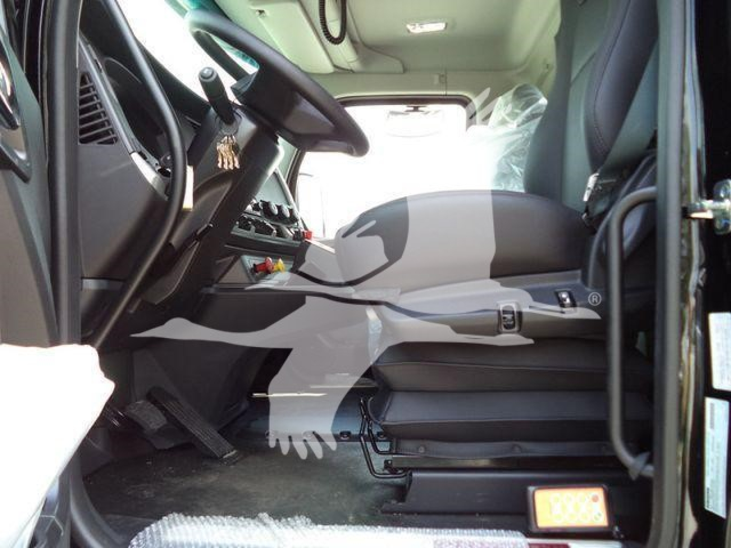 Kenworth T880 cab interior view showing driver seat, steering wheel, and dashboard from the doorway; visible seat controls and entry step.