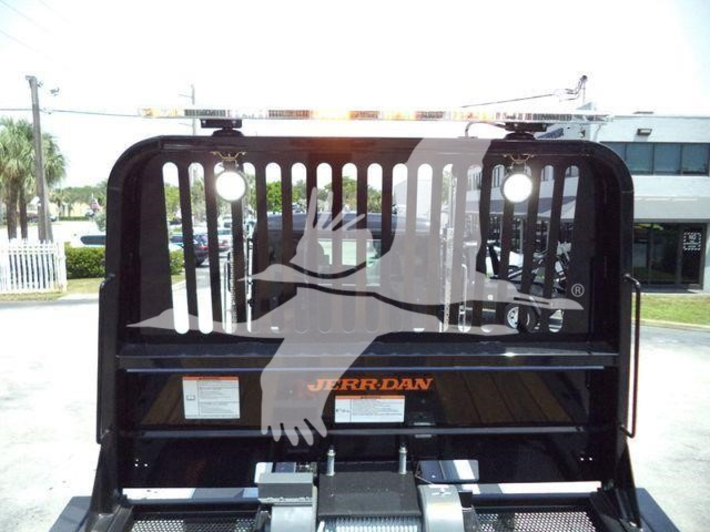 Kenworth T880 rollback truck rear view with JERR-DAN logo on spreader and safety cage, rear lights visible.
