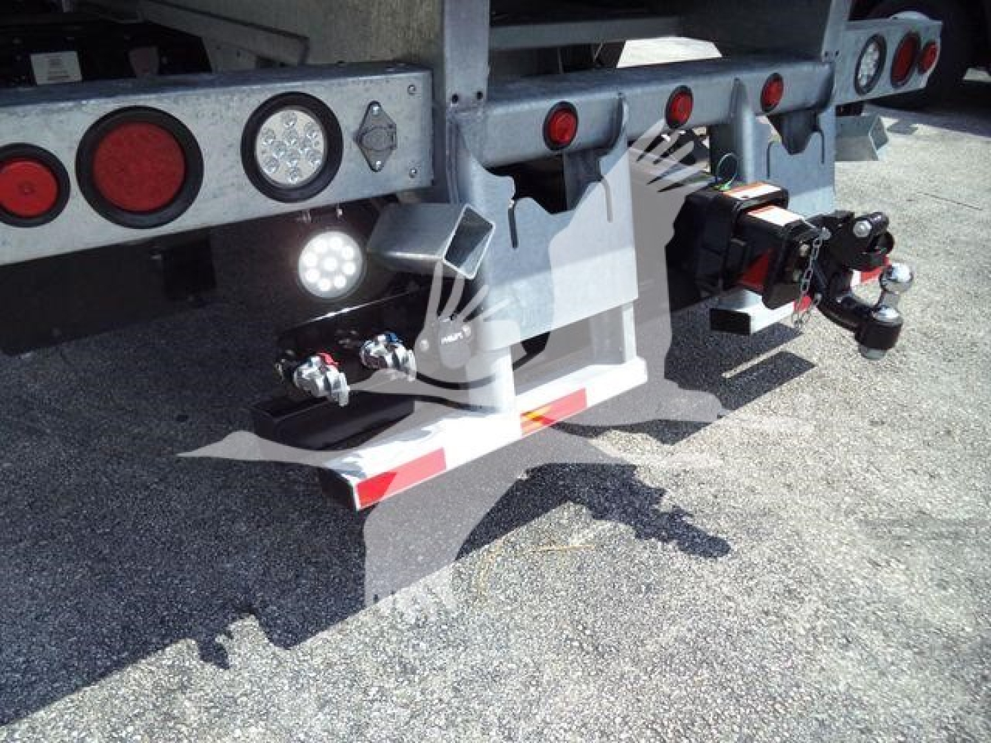Kenworth T880 rear undercarriage showing trailer hitch assembly, hydraulic lines, and lights with reflective tape on bumper.