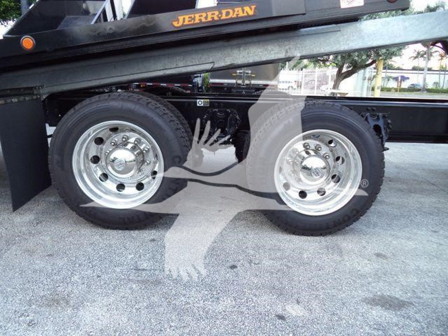 Kenworth T880 truck chassis and dual rear wheels on rollback equipment showing polished rims and fuel/air lines.
