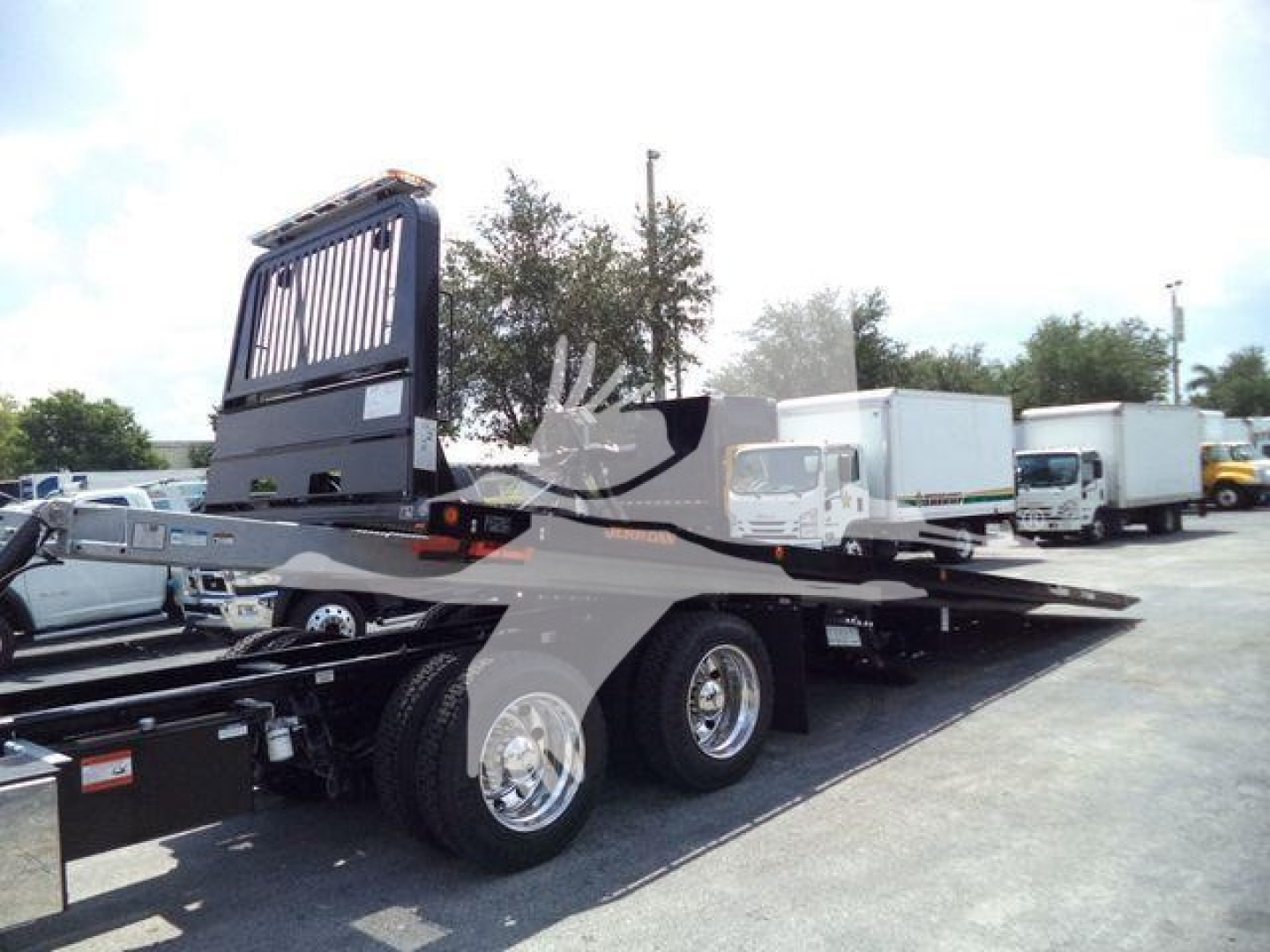 Kenworth T880 rollback truck chassis with flatbed and rear axle, various trucks in background
