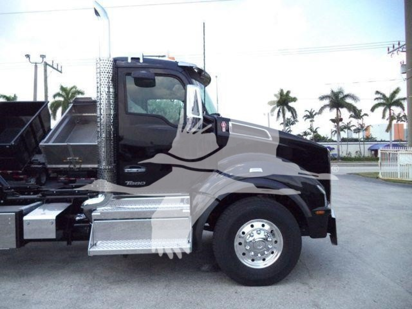 Kenworth T880 rollback truck side view showing chrome steps, black cab, silver fenders, and large wheel.