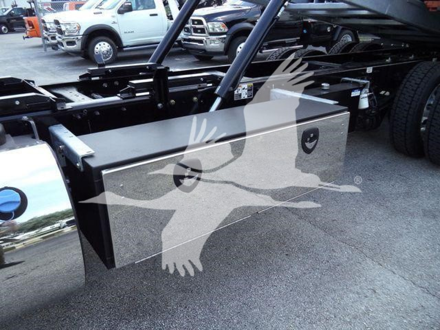 Kenworth T880 rollback truck frame with a large rectangular metal toolbox mounted under the cab, visible suspension and frame rails in background.