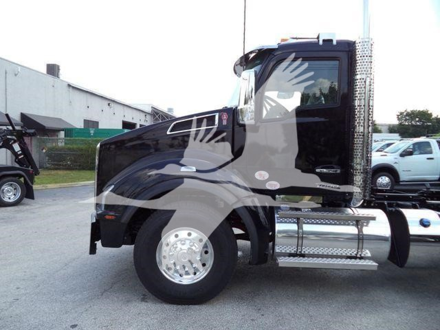 Kenworth T880 front/side view truck cab with chrome fuel tank and step, in a dealership lot.