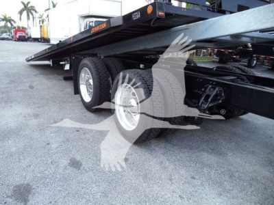 Kenworth T880 rollback truck chassis showing dual rear axles and flatbed equipment with wheels and suspension visible.