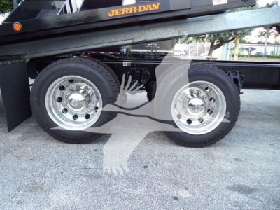 Kenworth T880 truck chassis and dual rear wheels on rollback equipment showing polished rims and fuel/air lines.