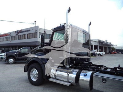 Kenworth T880 semi-truck cab and chassis shown in a dealership lot with chrome fuel tanks and tall exhaust stacks.