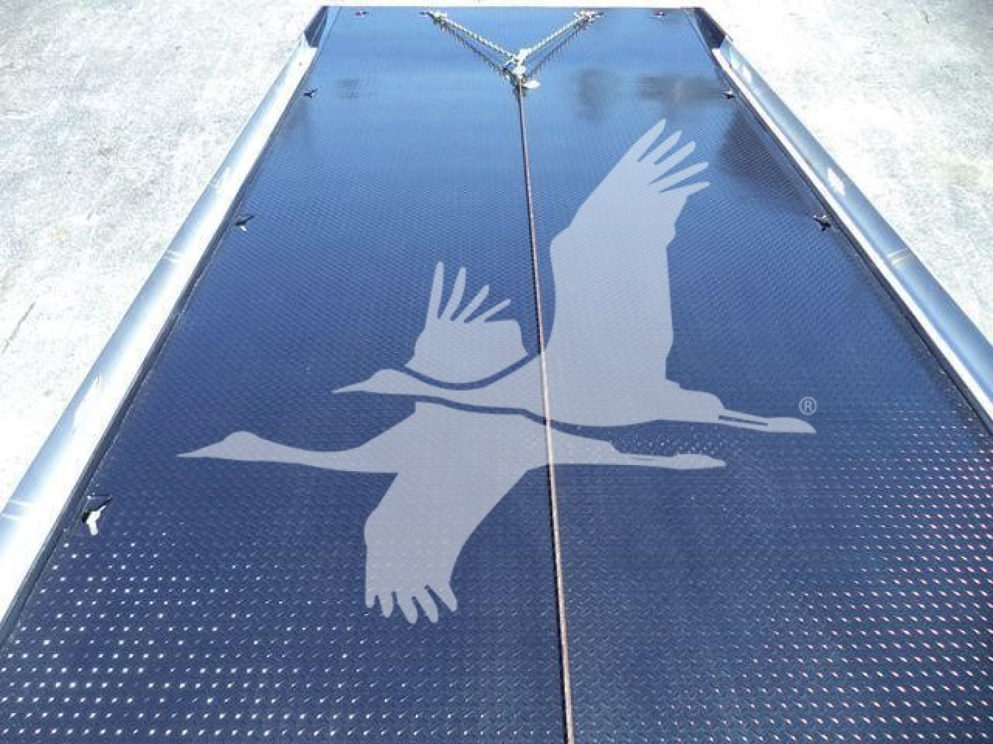 Kenworth rollback truck bed with blue diamond plate surface and white birds logo, split central seam.