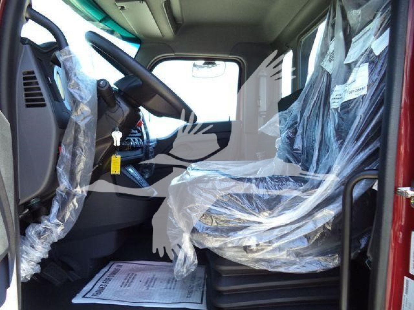Kenworth T280 truck cab interior with plastic-covered seat and plastic-wrapped controls visible, steering wheel, dashboard and passenger area.