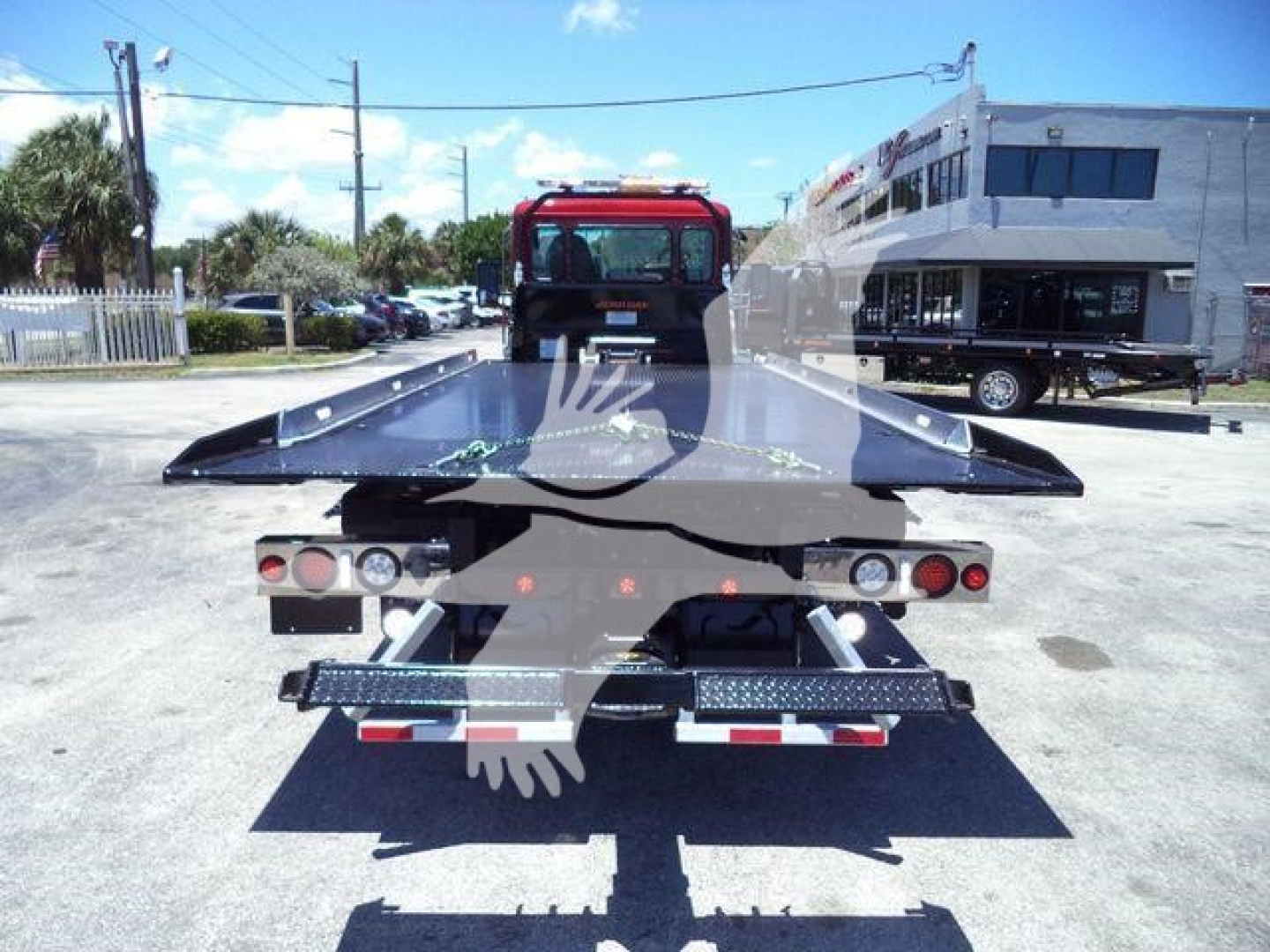 Flatbed tow truck bed rear view showing hydraulic ramp platforms and taillights.