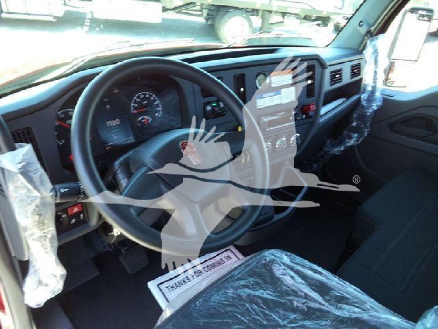 Kenworth T280 truck interior dashboard and steering wheel with protective plastic covering on seats and controls.