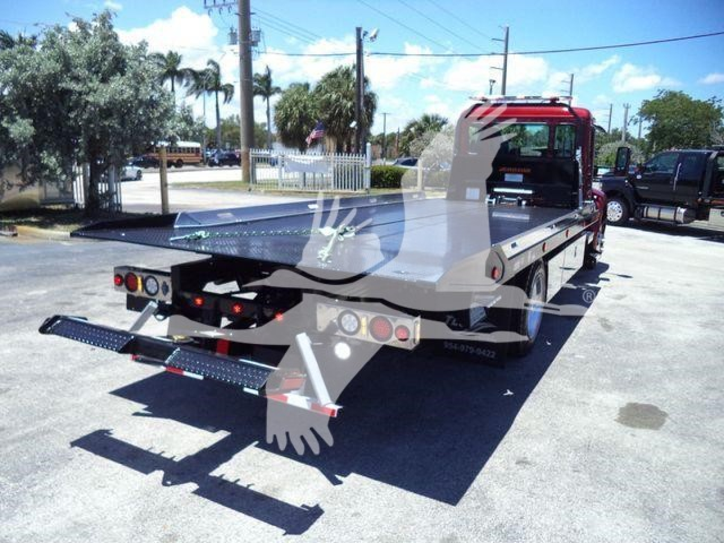 Kenworth T280 rollback tow truck rear view showing hydraulic bed and rear ramps with metal steps.