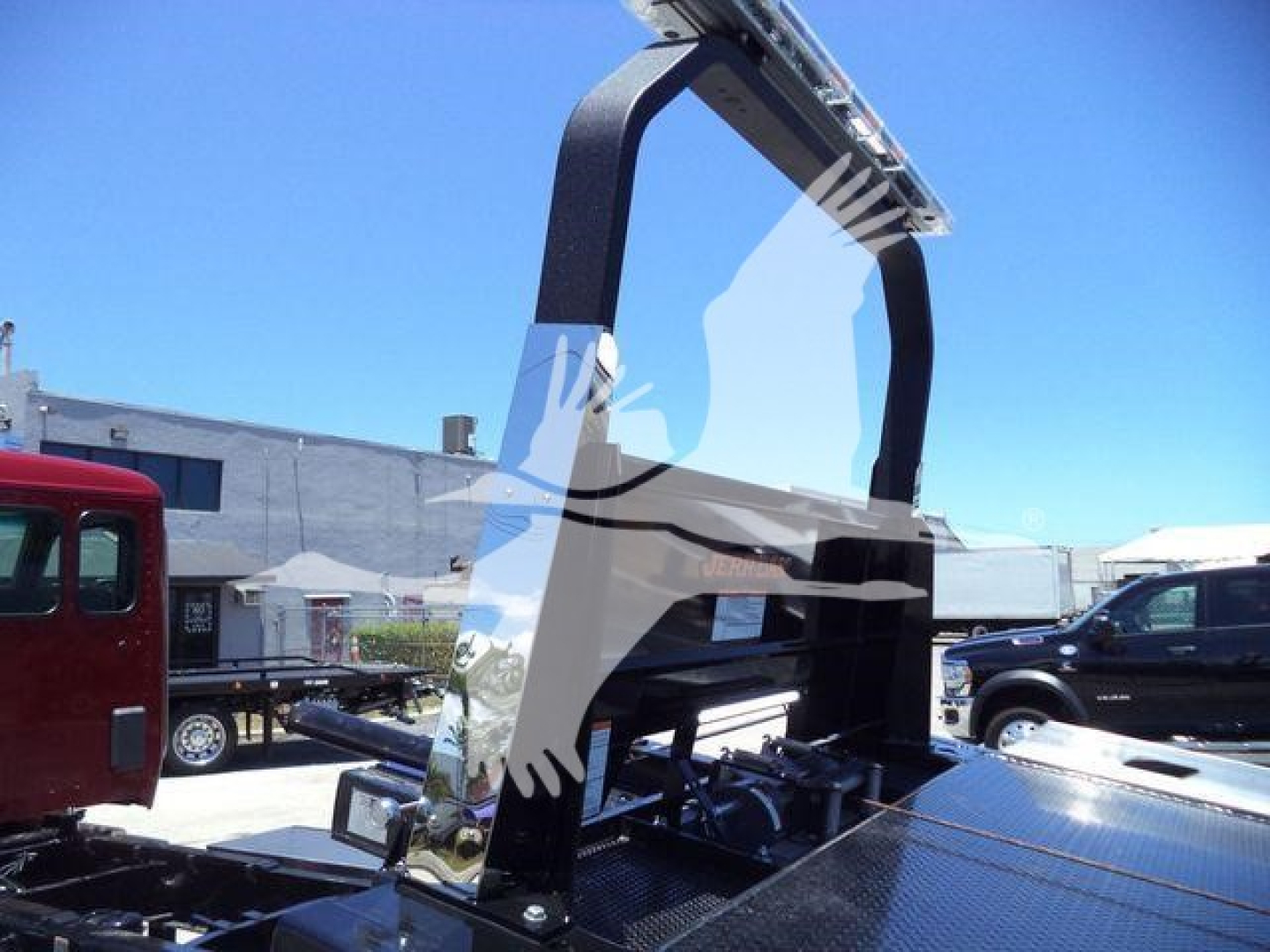 Kenworth T280 rollback truck chassis with hydraulic arm and platform, blue sky in background.