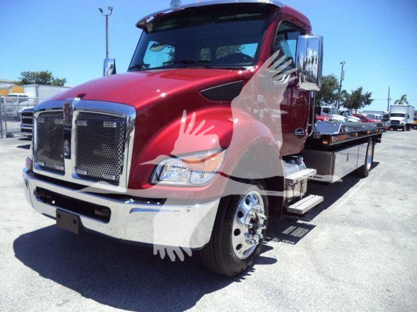 Kenworth T280 rollback tow truck front-left view showing red cab, chrome grille, large mirrors, and flatbed cargo area.
