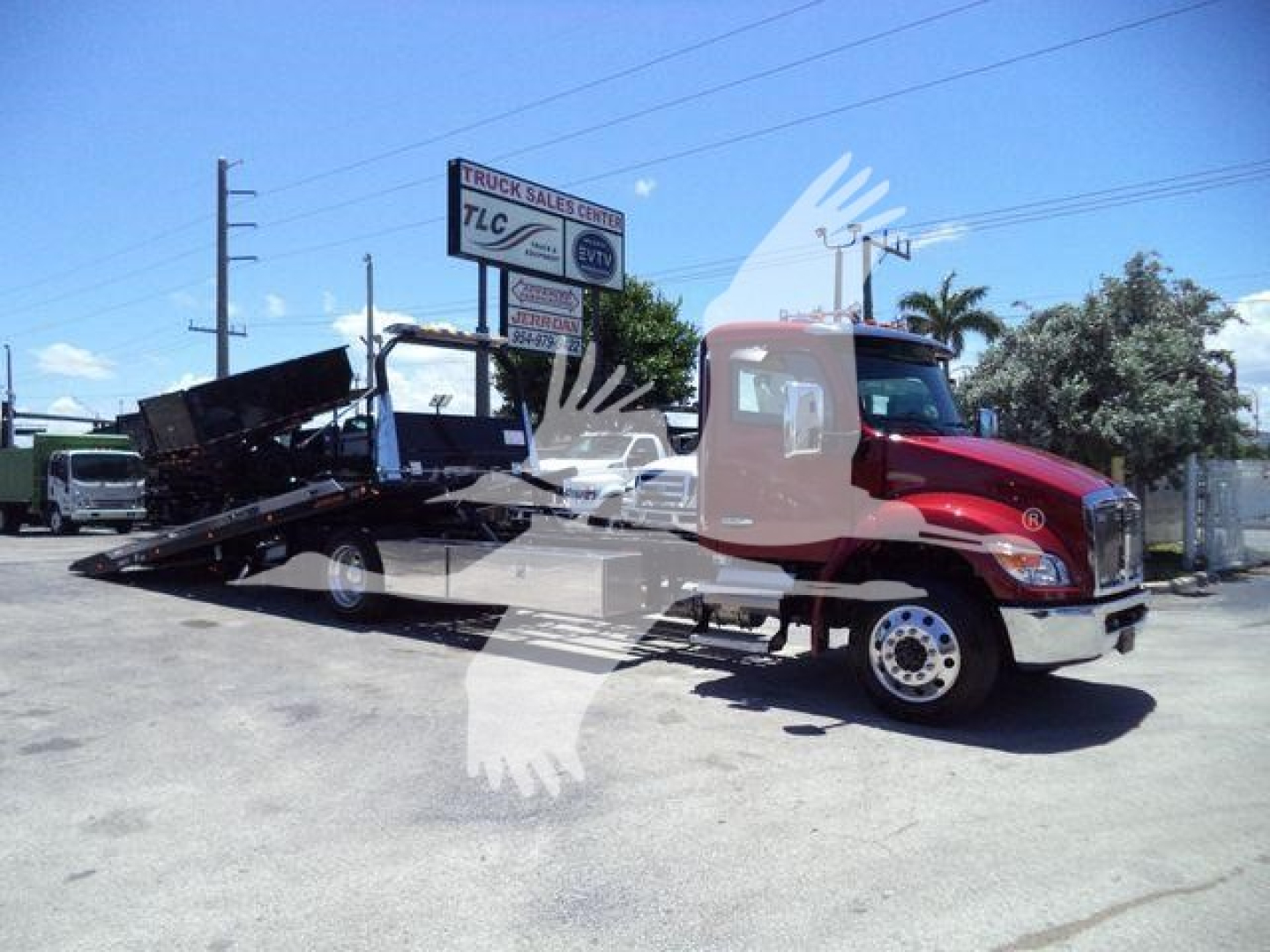 Kenworth T280 rollback truck in a dealership lot with flatbed bed extended, side view showing cab and utility equipment.