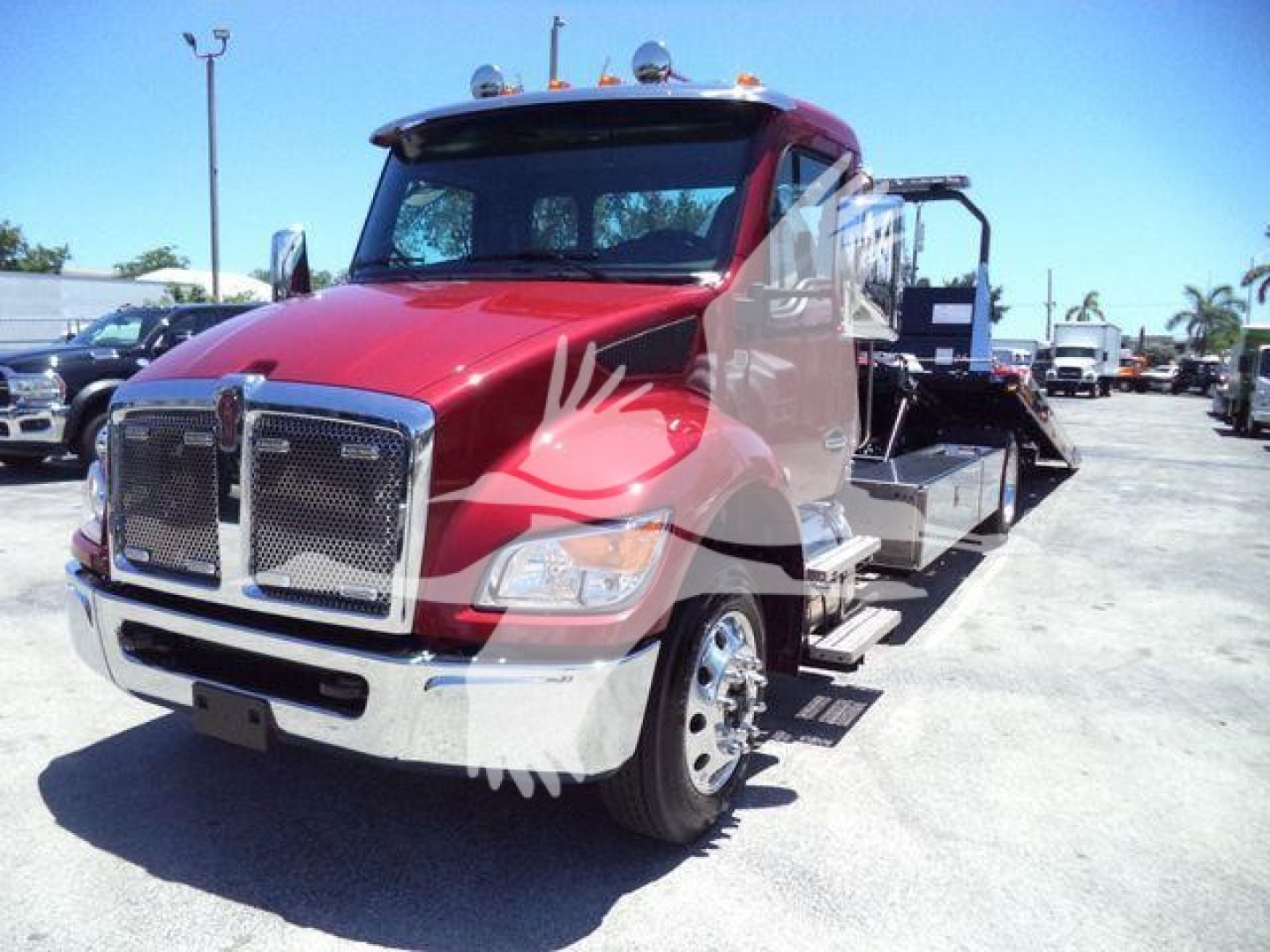 Truck bow view showing red Kenworth T280 rollback wrecker chassis and chrome grille, front bumper, headlamps, and flatbed with ramps.