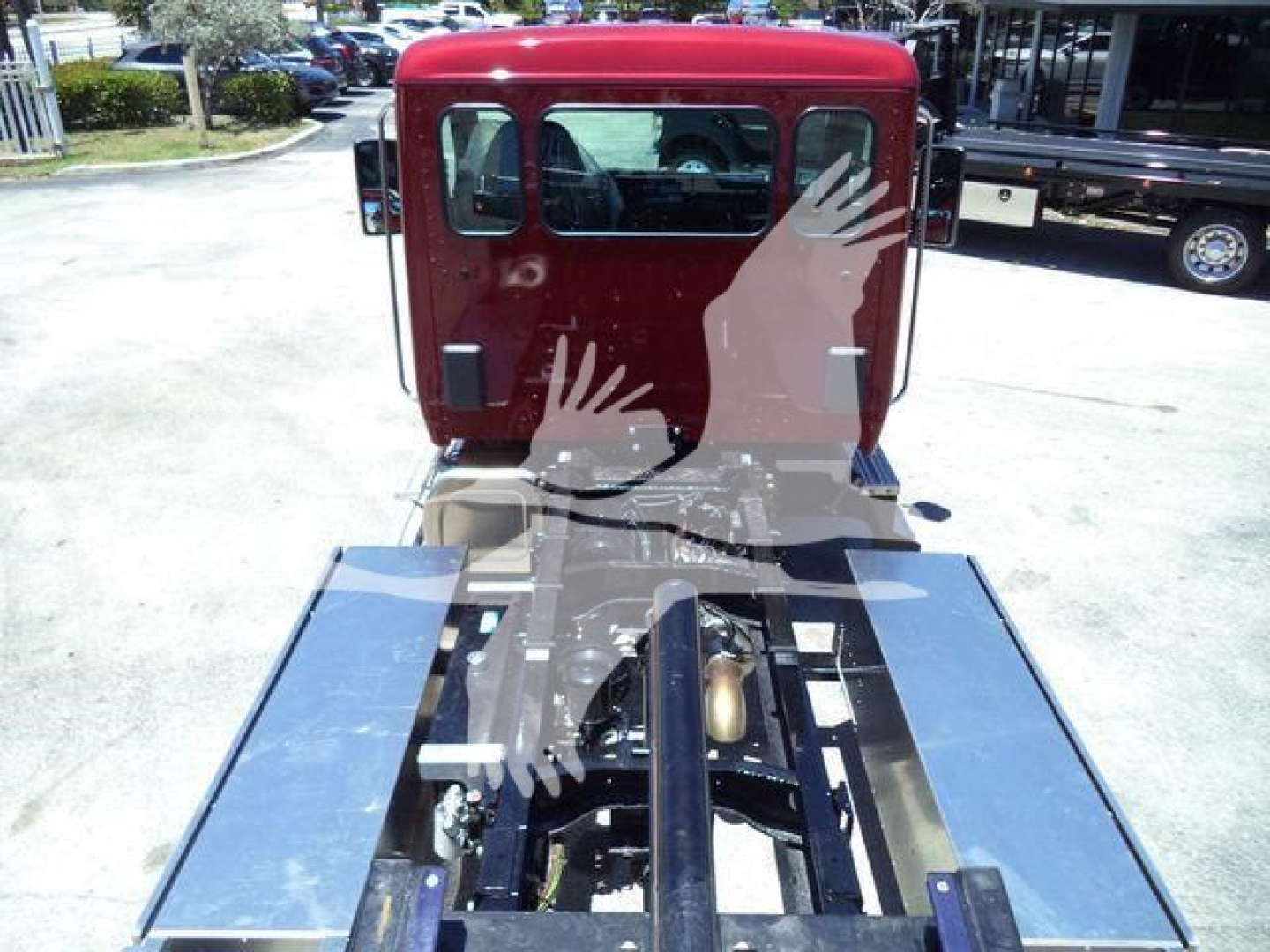 Truck cab rear view of a red 2025 Kenworth T280 rollback truck with chrome flatbed and mounting hardware visible.