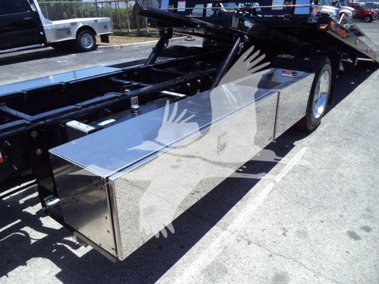 Truck service box mounted on a Kenworth T280 rollback chassis showing a polished metal toolbox under the frame.