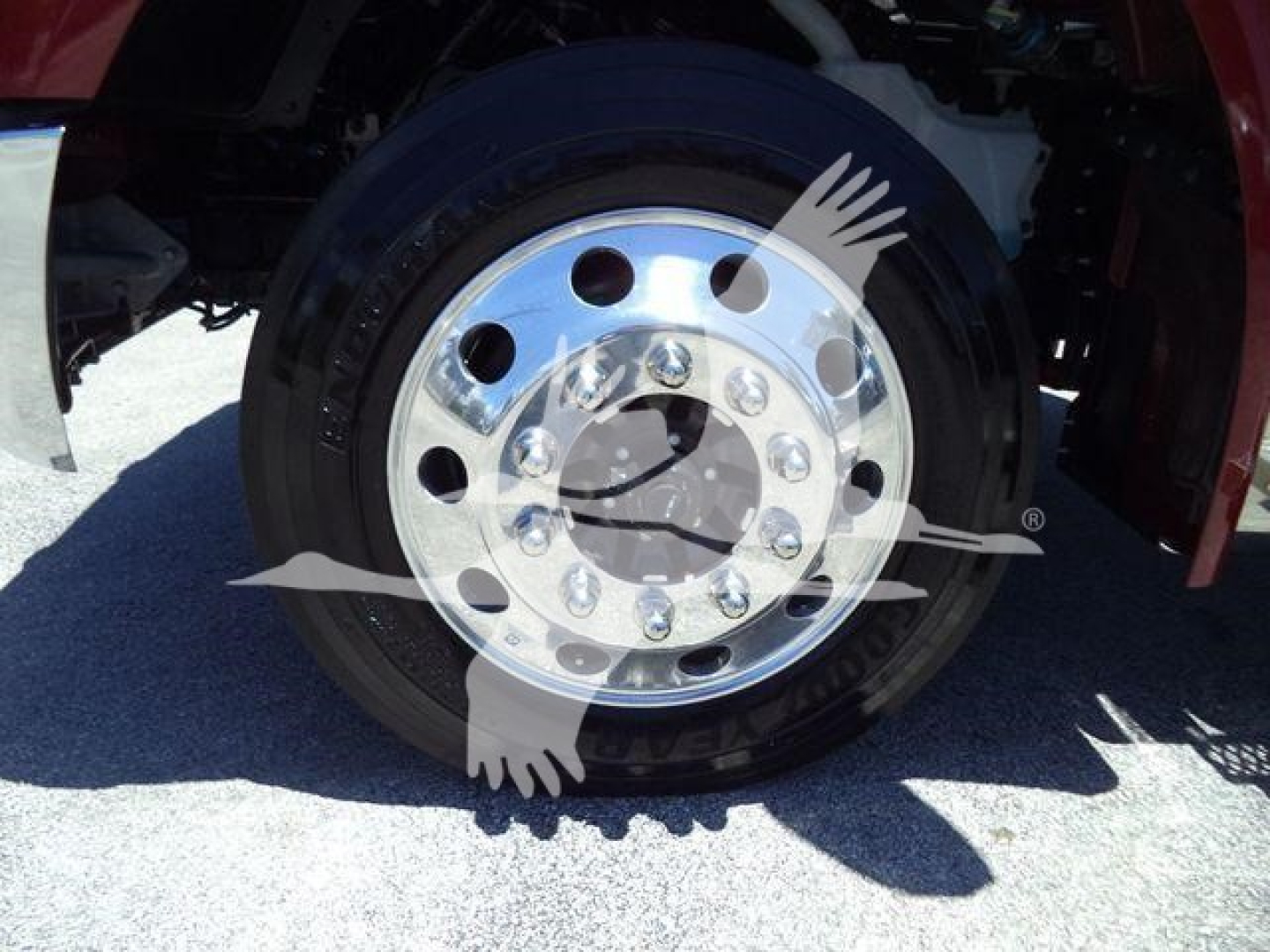 Vehicle wheel with polished rim and black tire, part of a Kenworth truck front wheel area.