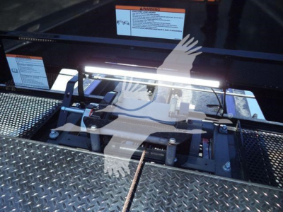 Kenworth T280 rollback tray with control bar and wiring visible; metallic diamond plate surface; warning labels and bright LED work light across top edge.