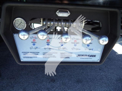 Kenworth T280 rollback controls panel with multiple gauges and labeled switches visible under a metal frame.