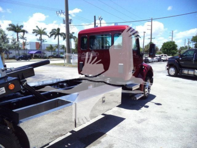 Kenworth T280 rollback truck chassis and cab in a dealership lot, with flatbed frame and side toolbox visible.