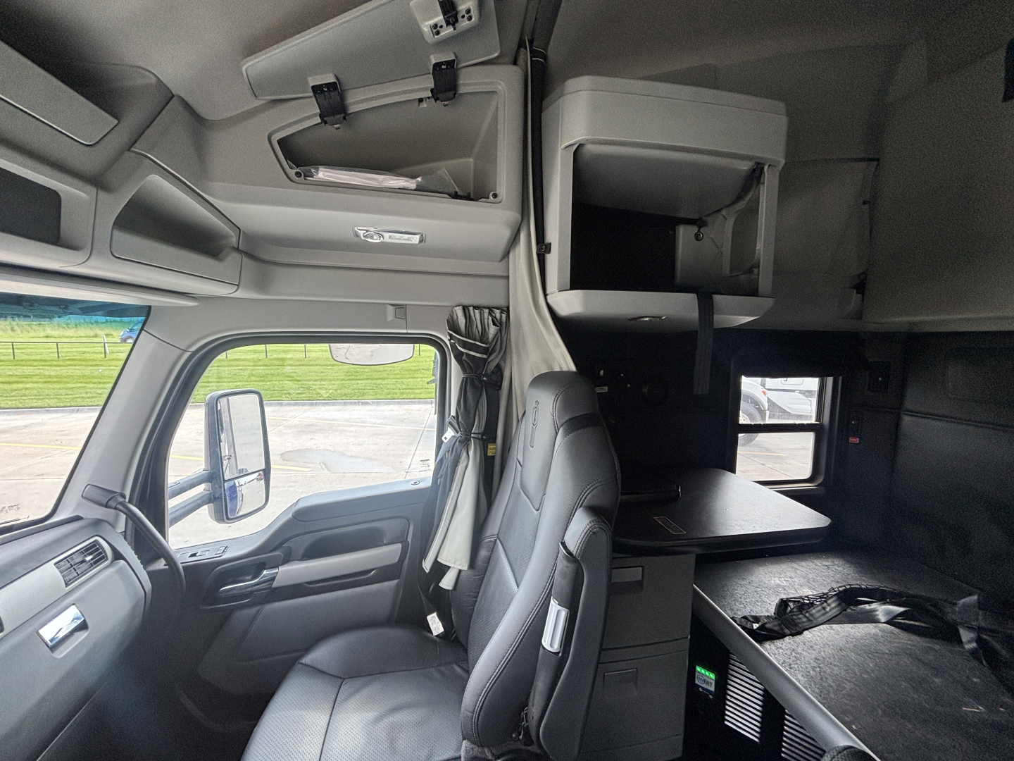 Kenworth T680 cab interior with sleeper area and storage shelf showing dashboard and bunk bed area.