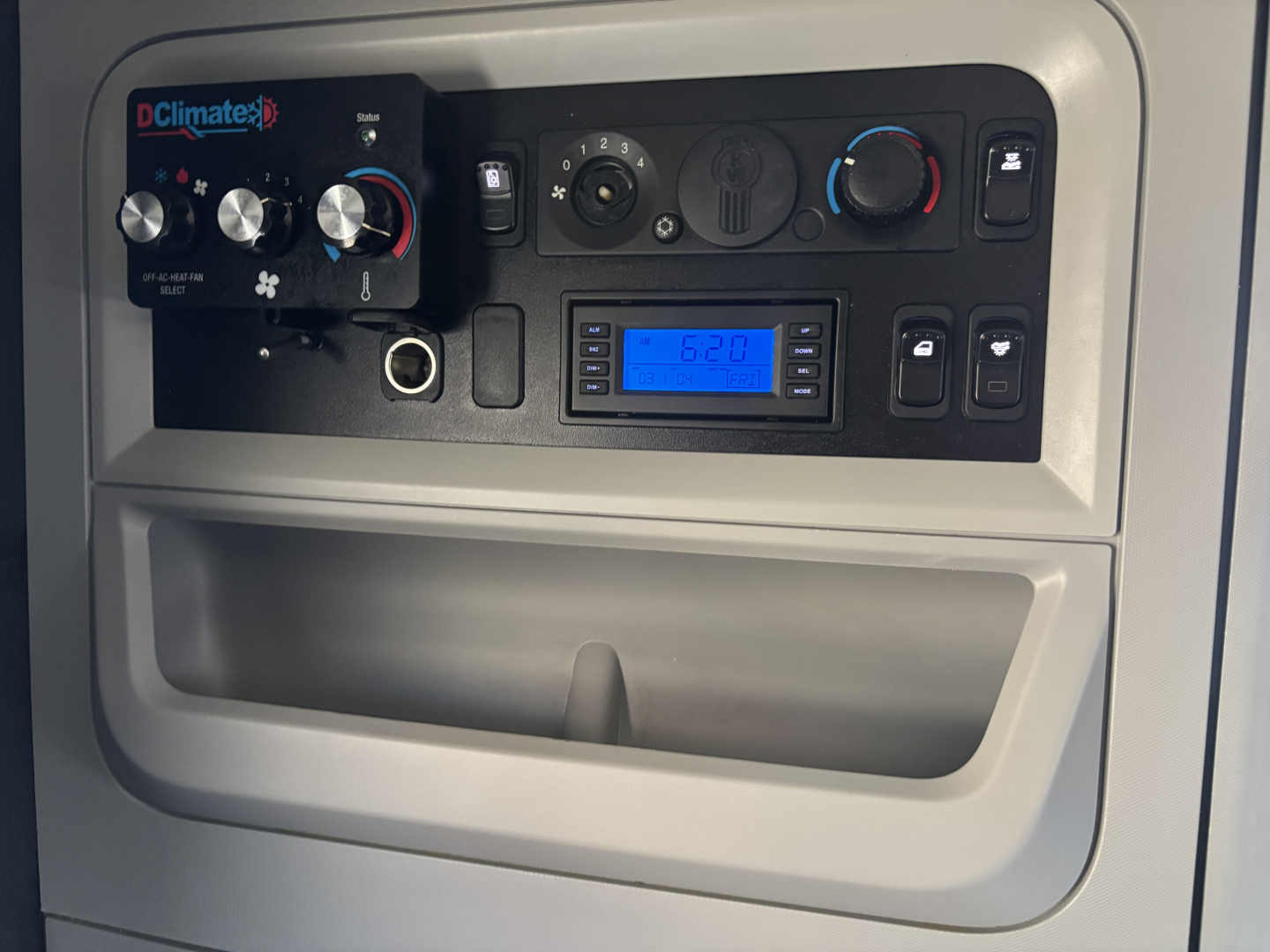 Kenworth T680 dash area showing climate controls, digital radio, and dashboard switches.