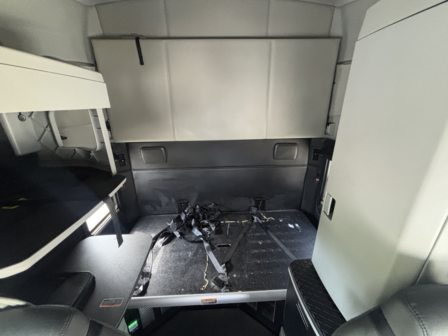 Kenworth T680 sleeper cab interior showing cargo area with seat belts and body panels, no visible text.