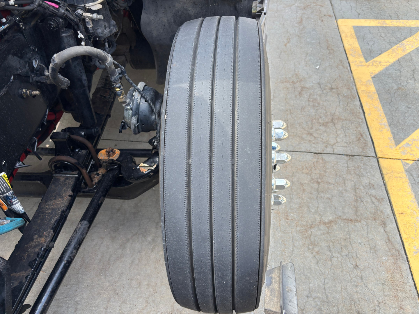 Kenworth T680 truck rear wheel drums and suspension visible with multiple lug nuts and drive components.