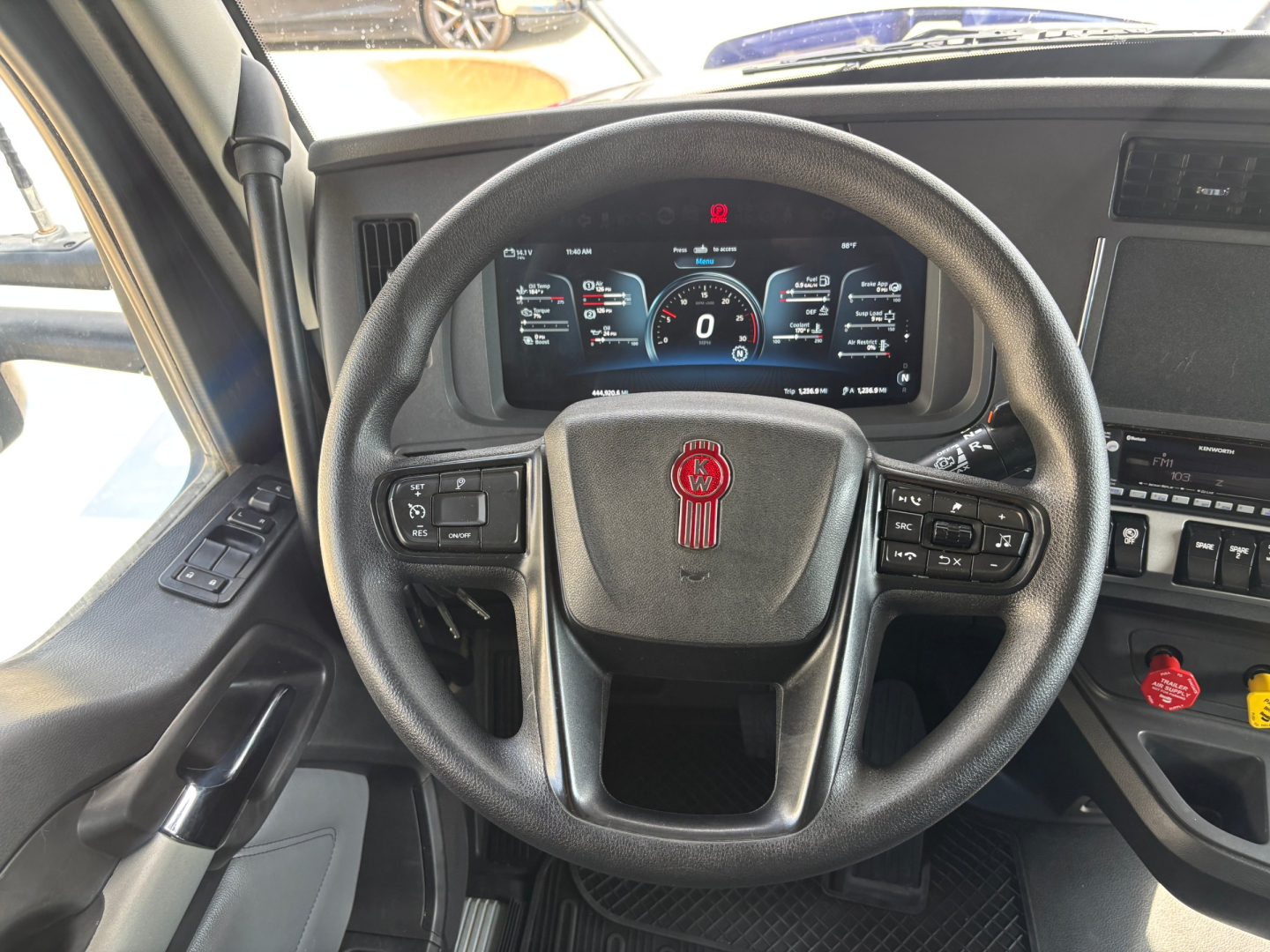 Kenworth T680 interior view of steering wheel and dashboard showing digital gauges and control stalks.