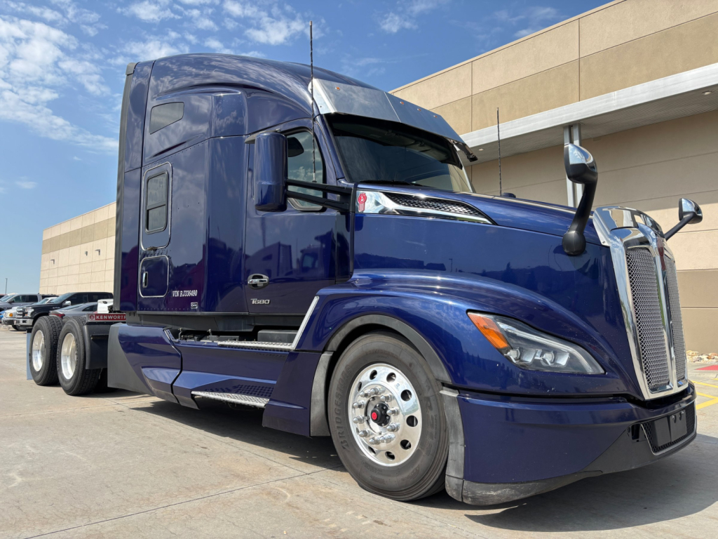 Kenworth T680 conventional sleeper truck in blue, front three-quarter view, showing cab and chrome wheels.