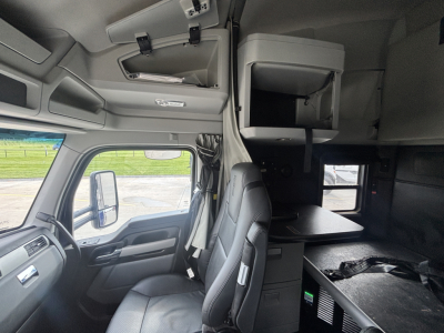 Kenworth T680 cab interior with sleeper area and storage shelf showing dashboard and bunk bed area.