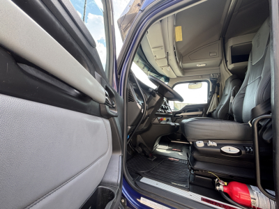 Kenworth T680 truck interior visible from open driver’s door showing steering wheel, dashboard, and front seats.