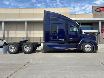 Kenworth T680 truck in blue exterior, side view showing cab, wheels, and fifth wheel area; no visible text legible on the vehicle.