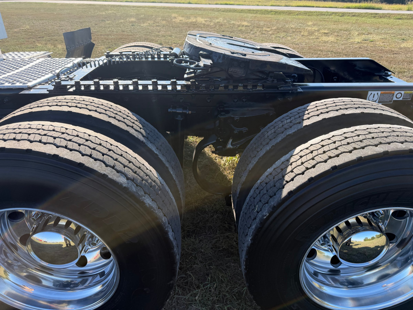 Kenworth T680 tractor chassis with dual rear axles and polished chrome wheels, showing tires and frame undercarriage.