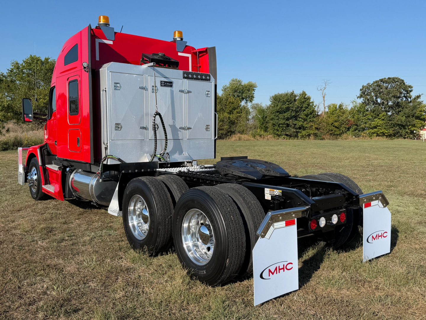 Kenworth T680 rear view showing fifth wheel area and dual rear axles with mud flaps and chrome wheels.