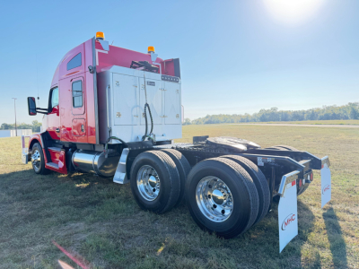 Kenworth T680 cab and dual rear axles from rear/left side showing cargo area and white mud flaps with CMGC text.