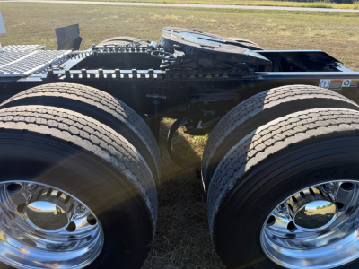 Kenworth T680 tractor chassis with dual rear axles and polished chrome wheels, showing tires and frame undercarriage.