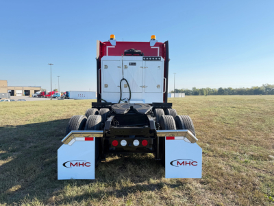 Kenworth T680 rear view showing dual rear axles and white mudflaps with MHC logos.