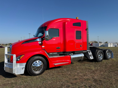 Kenworth T680 sleeper truck side view showing red exterior and chrome fuel tanks