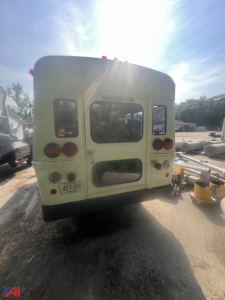 Rear view of a light-green 2003 Chevrolet Express bus with emergency door label, taillights, and a visible license plate.