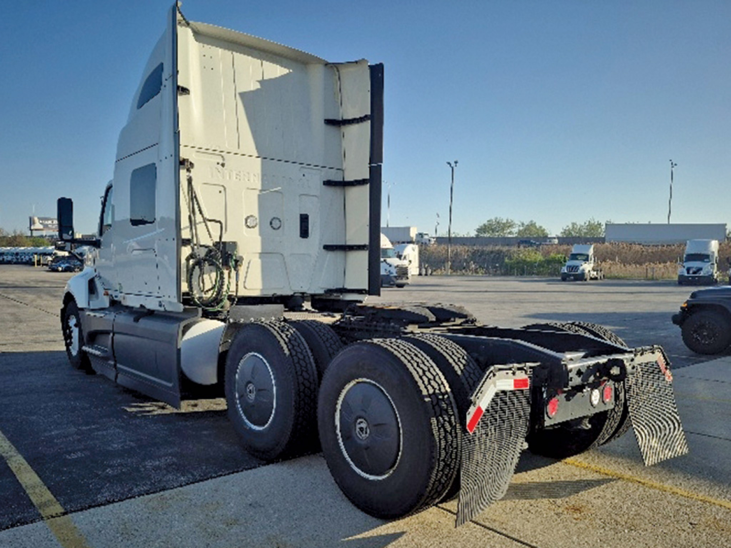 International LT625 sleeper tractor in a parking lot showing rear view with dual rear axles and mud flaps.